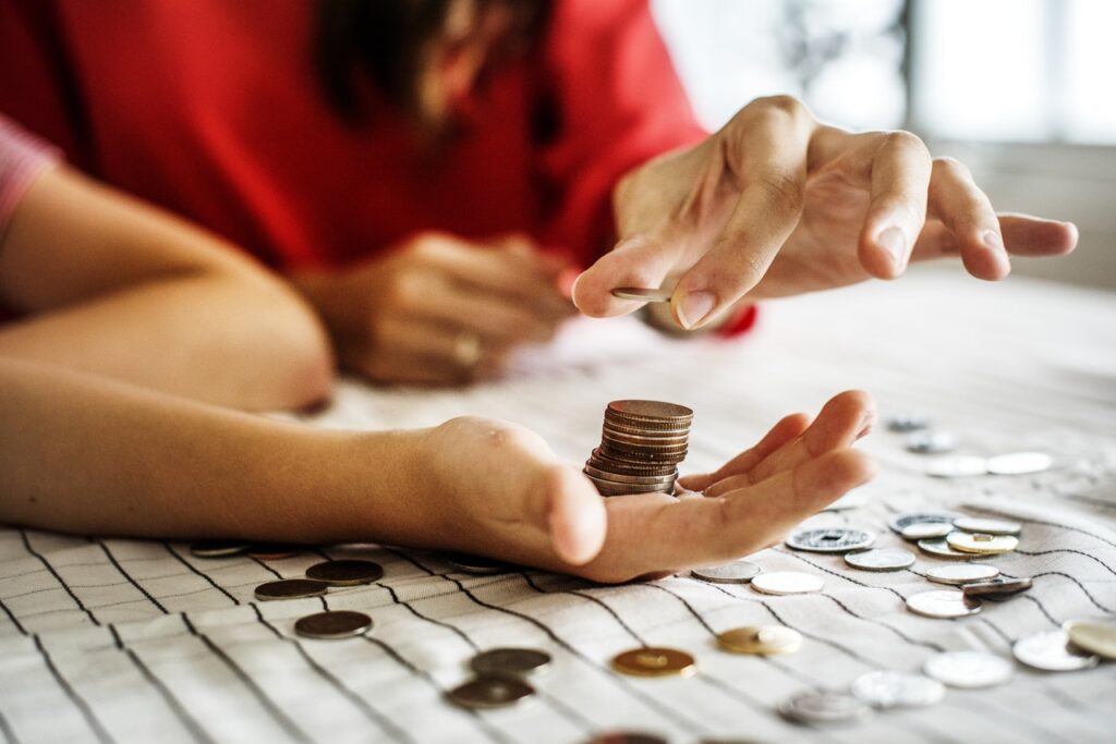 A person piling coins in another person's hand