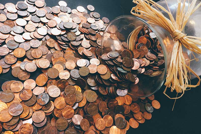 Image of a glass full of pennies spilling onto a table